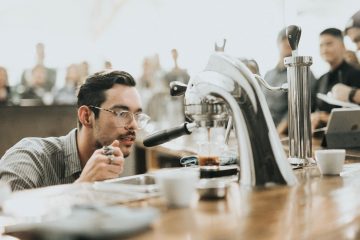 Mann mit Brille schaut sich eine Kaffeemaschine ganz genau an.