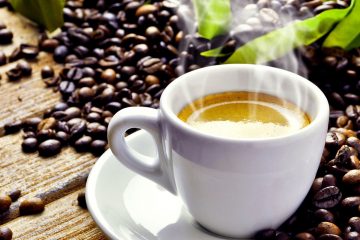Eine frische Tasse Kaffee und Kaffeebohnen im Hintergrund